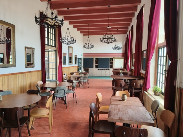 De Assendelftzaal: een lange zaal met roodgeschilderde balken, smeedijzeren kroonluchters en dieproze gordijnen.