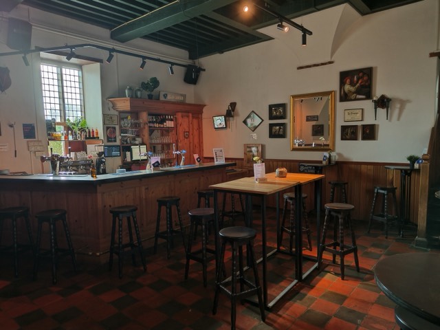 De bar van het slot: houten tap met barkrukken op een rood geblokte plavuizenvloer.